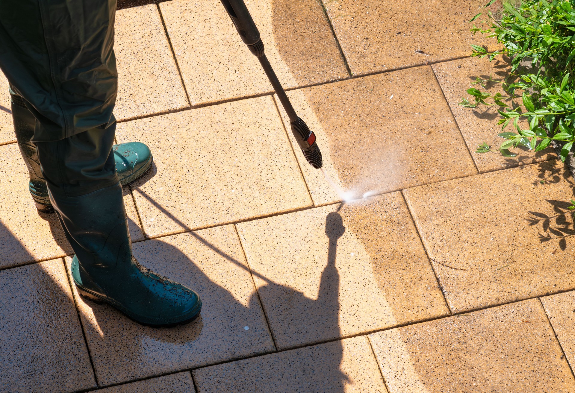 Une personne enlève la saleté tenace des carreaux de patio à l’aide d’un nettoyeur haute pression. Effet avant-après clair