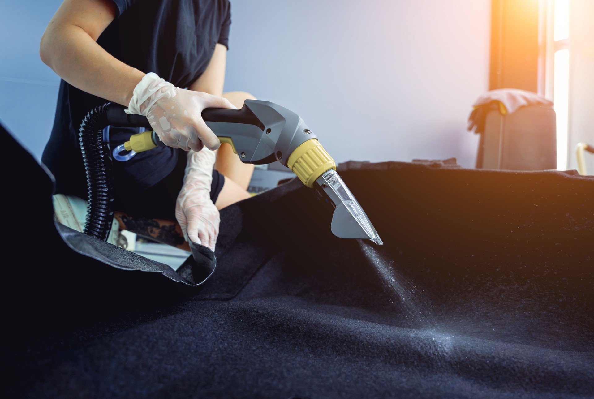 Jeune femme nettoyant les détails de la voiture avec un aspirateur de lavage